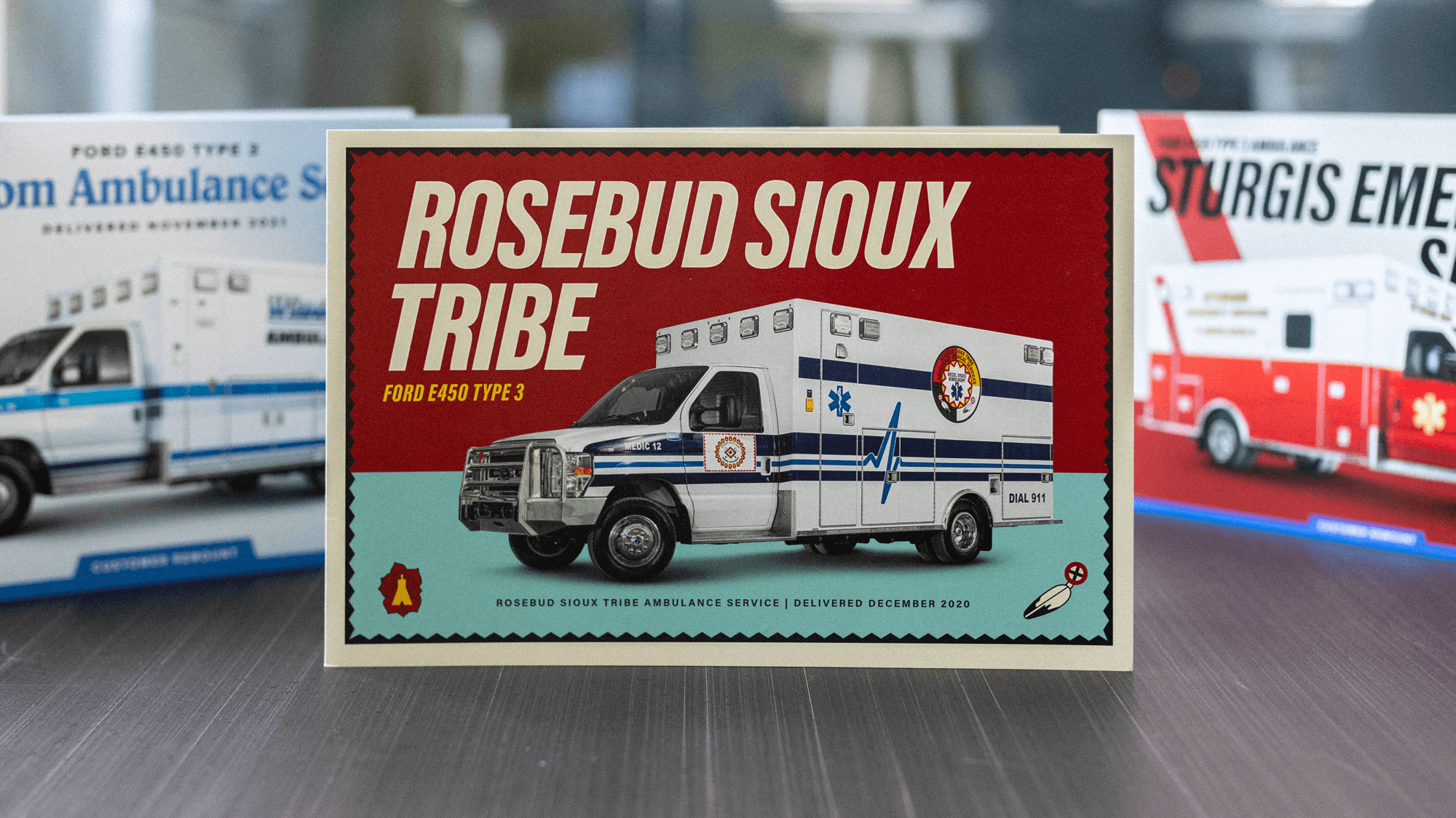 Photograph of three cards set up on table top, featuring Rosebud Sioux Tribe in middle